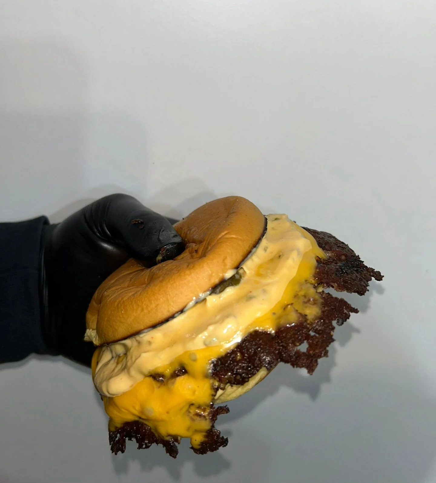 Un smash au cheddar coulant tenu à la main